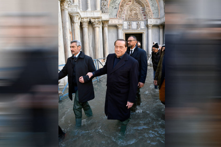 Silvio Berlusconi (M, 81), ehemaliger Ministerpräsident von Italien und Forza Italia-Parteichef, geht in Gummistiefeln bei Hochwasser über den Markusplatz.