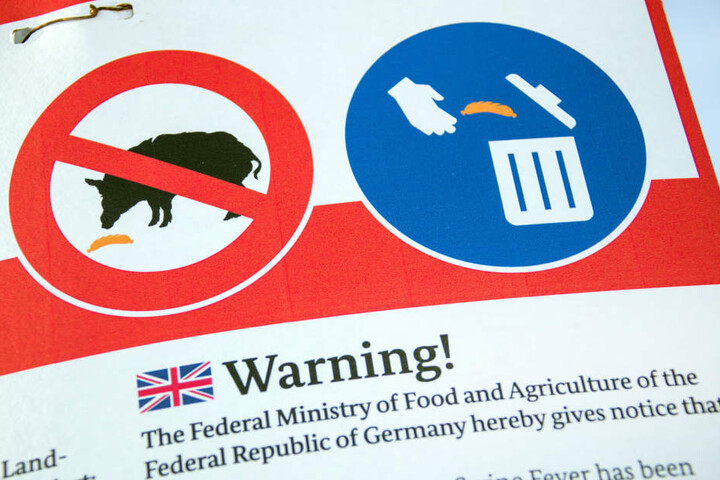 Eine Tafel informiert in verschiedenen Sprachen über Maßnahmen gegen die Ausbreitung der Schweinepest.