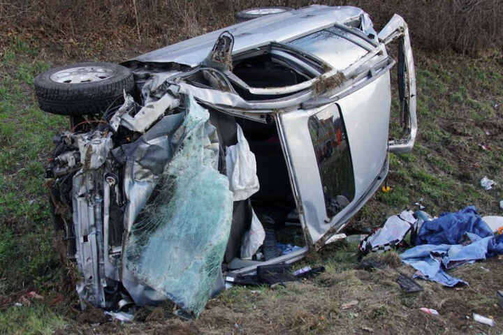 Das Wrack des Autos liegt neben der Fahrbahn in einem Grünstreifen.