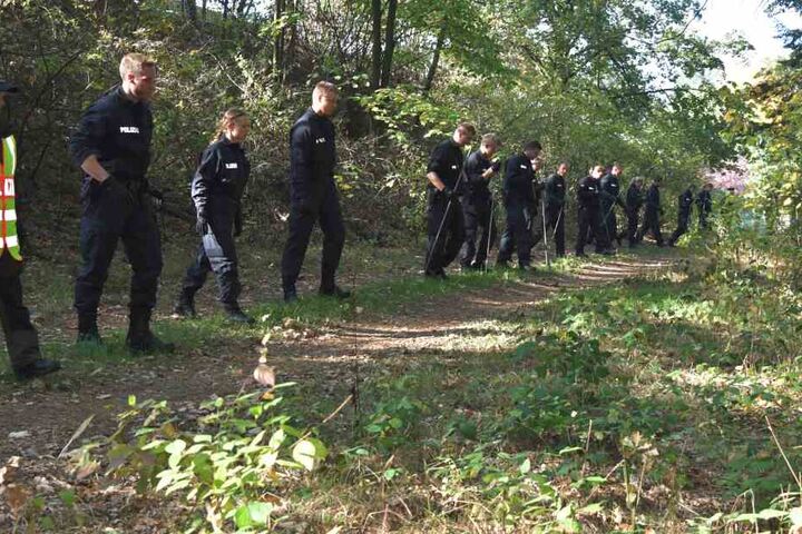 Die Beamten durchforsten das Waldstück, in dem die Knochen gefunden wurden.