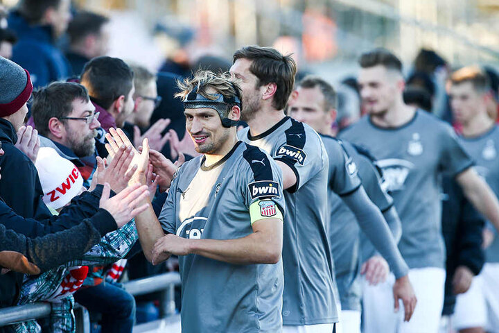 "Maskenmann" Toni Wachsmuth klatscht nach der Partie mit den Zwickauer Fans ab.