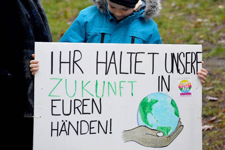 Schleswig-Holstein, Kiel: Mit einem Schild mit der Aufschrift "Ihr haltet unsere Zukunft in den Händen" steht ein Schüler bei einem Demonstrationszug.