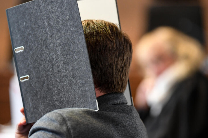 Der Angeklagte hält beim Prozess im Mai 2015 einen Aktenordner vor sein Gesicht.