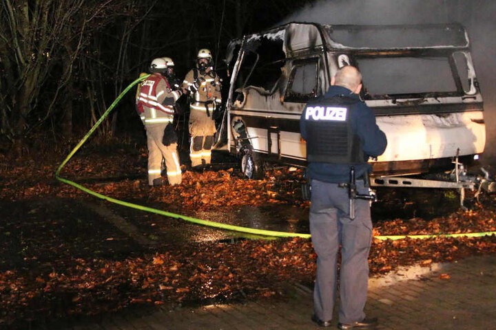Polizei und Feuerwehr begutachten den zerstörten Wohnwagen.