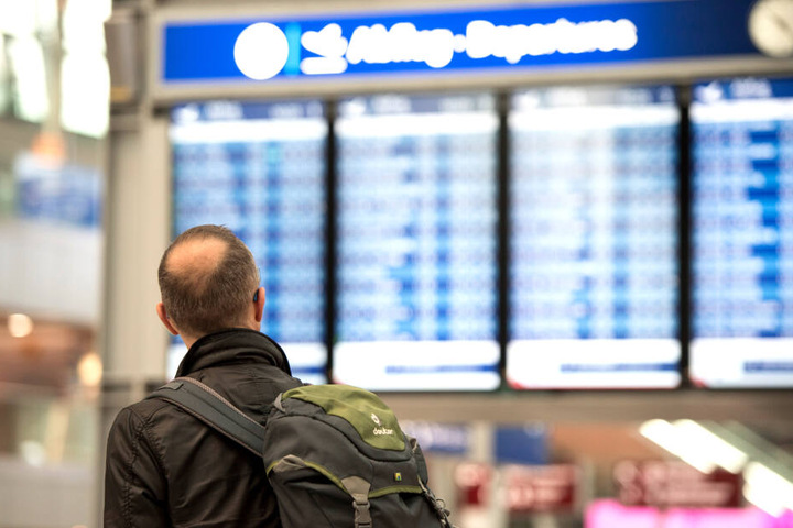 Ein Passagier blickt im Flughafen in Düsseldorf auf eine Anzeigetafel.