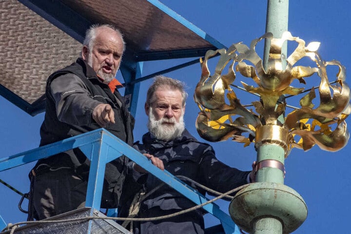 Zwei Arbeiter befestigten die goldene Krone auf dem Rathausdach.