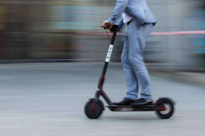 Ein Mann fährt auf einem E-Scooter.