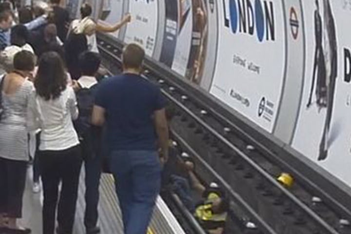 Die Passanten schauen zu, als der Retter auf die U-Bahn-Gleise springt, um den Mann zu retten.