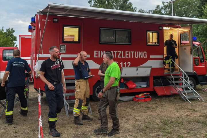 Die Einsatzleitung der Feuerwehr steht am späten Abend auf einem Dorfplatz in Byhleguhre am Rande des Spreewaldes.