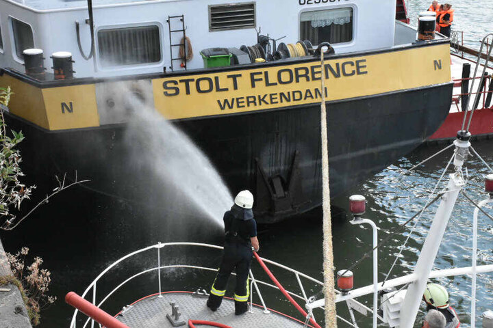 Feuerwehrleute löschen den Schiffsbrand.