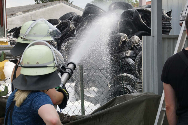 Einsatzkräfte versprühen Schaum, um ein Übergreifen der Flammen zu verhindern.