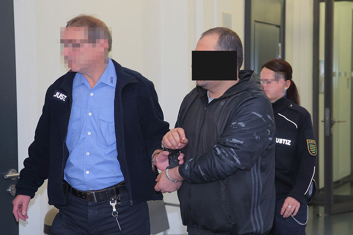 Hier wird einer der sechs Angeklagten zum Prozess gebracht.