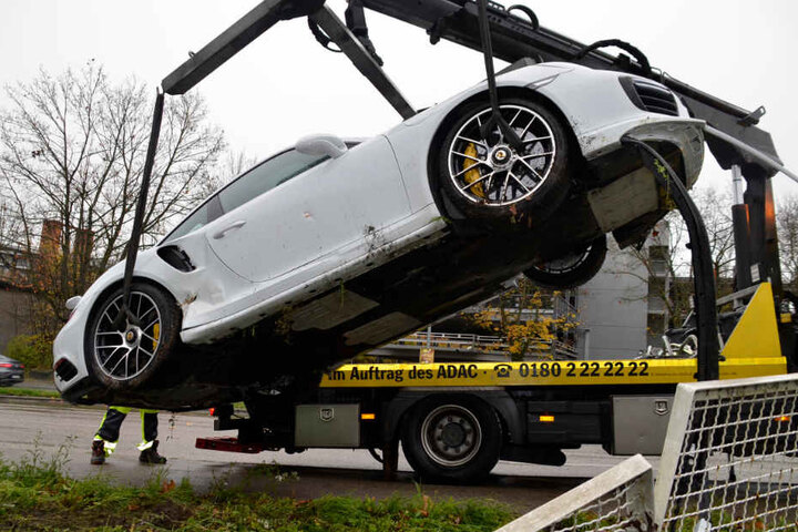 Porsche flieg: Am Kranhaken des Abschleppwagens wird der demolierte Flitzer nach oben gehievt.