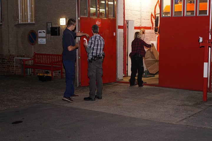 Einer der Feuerwehrmänner beschreibt einen Kripo-Beamten den Tathergang, während eine Kollegin Einbruchswerkzeug aus einer Tüte auspackt.