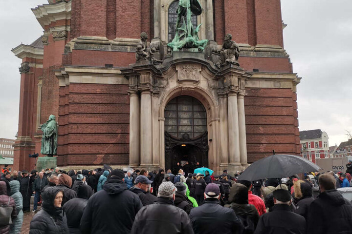 Trotz des Regens stehen zahlreiche Fans vor dem Michel.