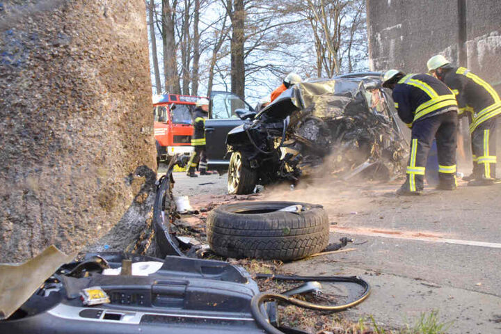 Einsatzkräfte stehen vor dem zerstörten Autowrack.