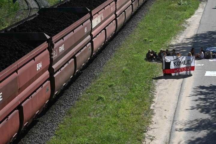 Auf den Bahnschienen neben der Blockad fährt ein Kohlezug der RWE.