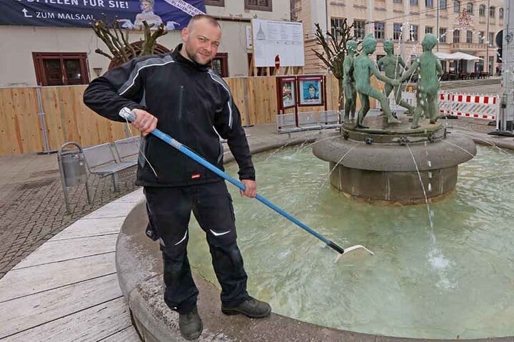Martin Lang säubert mit einem Kescher den sprudelnden Kinderbrunnen in der City.