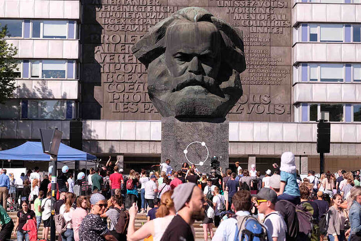 Besucher des Festivals "Kosmos Chemnitz - Wir bleiben mehr" stehen am Karl-Marx-Monument. Mit dem Festival soll erneut ein Zeichen für eine friedliche, weltoffene Gesellschaft gesetzt werden.