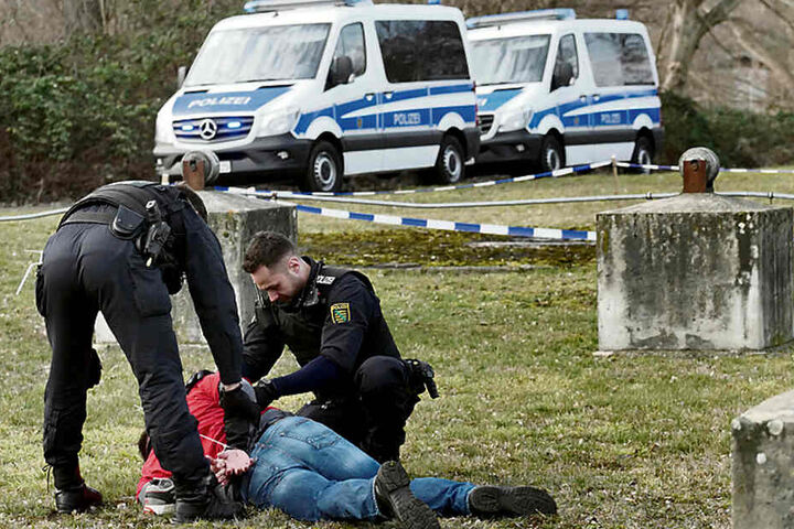 Zwei Bereitschaftspolizisten haben nach einem simulierten Straßenraub unter Jugendlichen einen Verdächtigen am Boden fixiert.