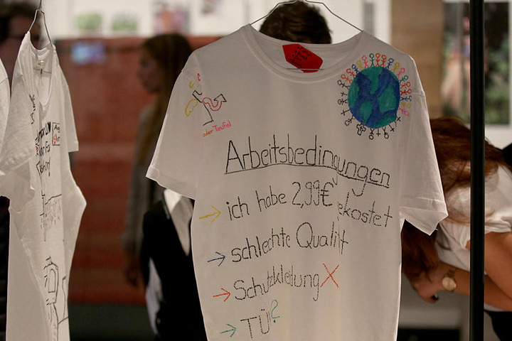 Auf einem T-Shirt werden die Produktionsbedingungen und die Preispolitik bei Billigtextilien angeprangert.