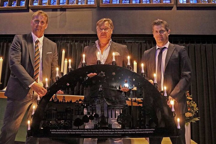 Rene Groh (39, l.) hat den Schwibbogen auf Initiative der Macher der Schlossweihnacht wie Jörg Hempel (42, r.) hergestellt und an die Organisatoren des Berliner Weihnachtsmarktes wie Michael Roden (55) übergeben.
