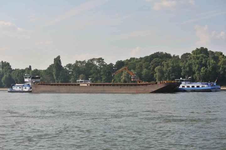 Mehrere Bergeschiffe entladen das havarierte Schiff auf dem Rhein in Köln-Rodenkirchen.