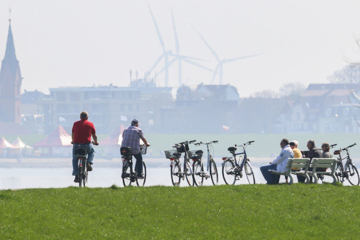 Radfahrer nutzen die Sonne an der Strandpromenade von Cuxhaven.