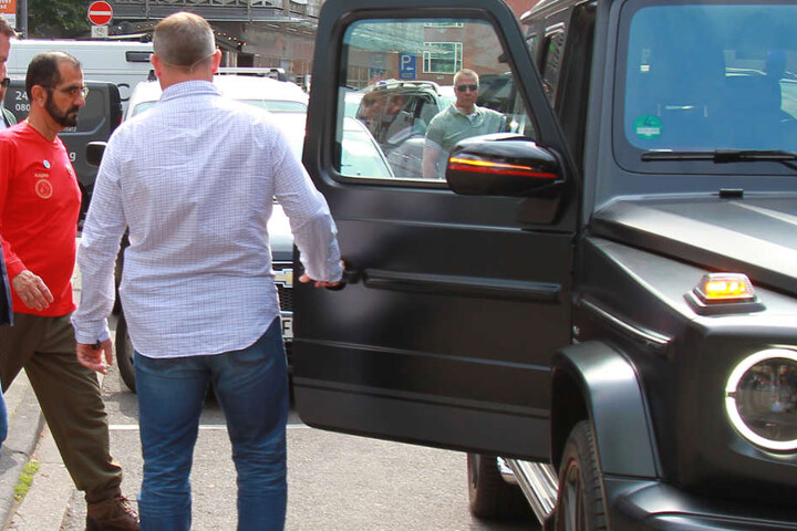 Unter Schutz der Leibwächter steigt der Emir von Dubai nach dem Besuch in Köln wieder in den Mercedes G AMG.