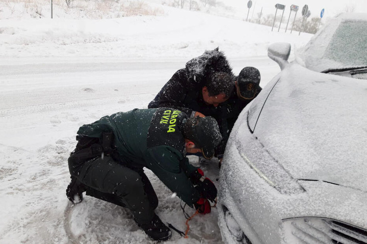 Zwei Beamte der Guardia Civil helfen einem Fahrer in Carinena beim Anlegen der Schneeketten.