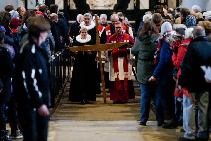 Bischöfin Kirsten Fehrs und Erzbischof Stefan Heße tragen vor dem Beginn des ökumenischen Kreuzwegs ein Holzkreuz durch die Jakobikirche.