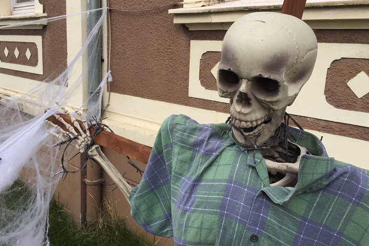 Vor dem Haus steht eine Skelett-Figur mit Stacheldraht um den Hals.