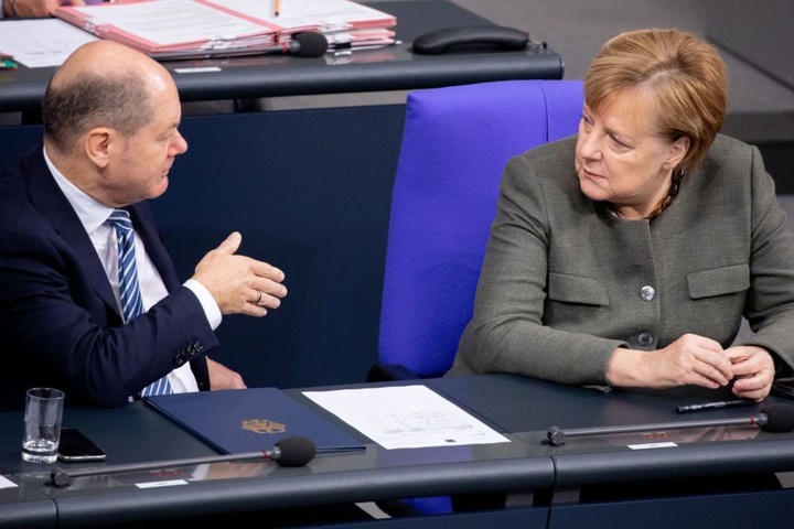 Olaf Scholz sitzt im Bundestag neben der Kanzlerin Angela Merkel. Beide sind aktuell in Argentinien.