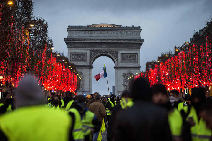 Demonstranten stehen vor dem Arc de Triomphe.
