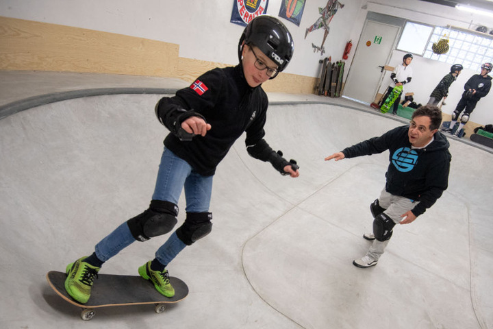 Ein Lehrer leitet während der Skateboard-AG einen Schüler des Gymnasiums beim Pushen im Bowl an.