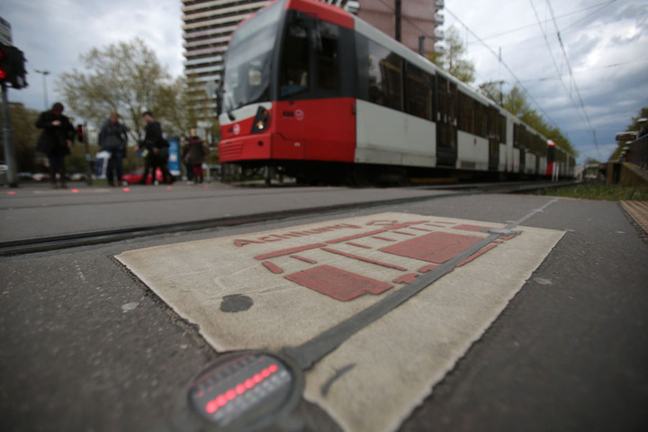 Piktogramme und Lämpchen im Asphalt warnen Kölner vor der Straßenbahn.