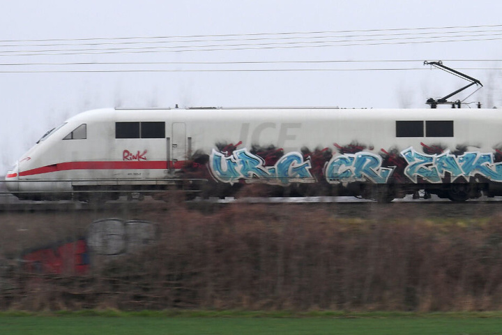 Ein mit Graffiti besprühter Zug fährt an einer Strecke.
