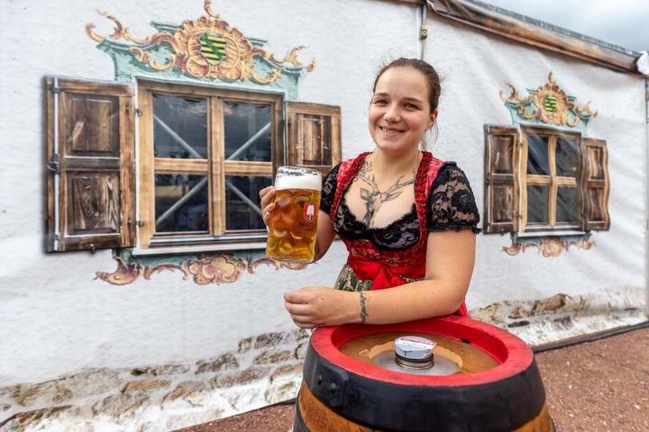 Service-Kraft Carolin (26) mit einer Maß Bier und einem Bierfass vor dem Festzelt.