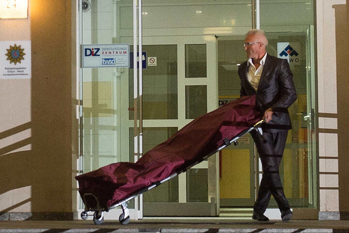 Ein Bestatter bringt die Leiche der 48-Jährigen aus dem Gebäude.