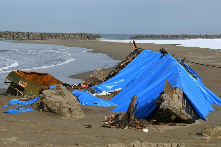 Das auseinandergebrochene Holzboot liegt am Strand in Kanazawa, Präfektur Ishikawa (Japan).