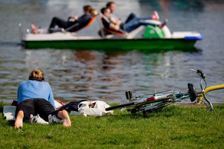 Eine Frau liegt im Treptower Park an der Spree.