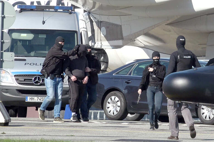 Ein mutmaßliches Mitglied der Terrormiliz IS (2.v.l.) wird auf dem Flughafen Hamburg zu einem Hubschrauber der Bundespolizei gebracht. Mit der Maschine wurde der Verdächtige nach Karlsruhe geflogen werden, wo ein Ermittlungsrichter beim Bundesgerichtshof