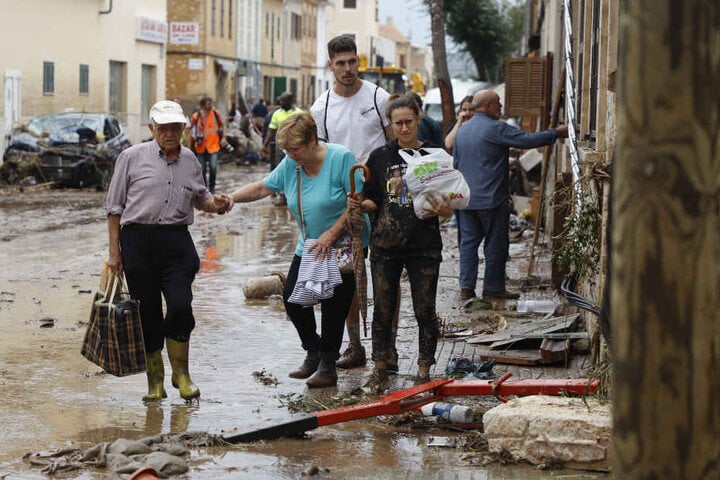 Anwohner gehen nach einem schweren Unwetter über eine mit Trümmern bedeckte Straße.
