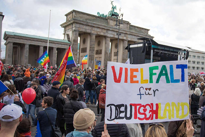 Eine Frau mit einem Transparent "Vielfalt für Deutschland" hat sich mit zahlreichen Menschen am Brandenburger Tor versammelt.