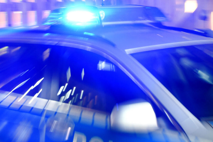 Ein Polizeifahrzeug steht mit eingeschaltetem Blaulicht auf einer Straße (Symbolbild).