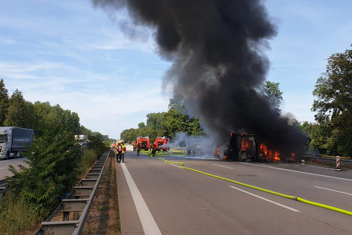 Feuerwehrleute löschen das brennende Fahrzeug.