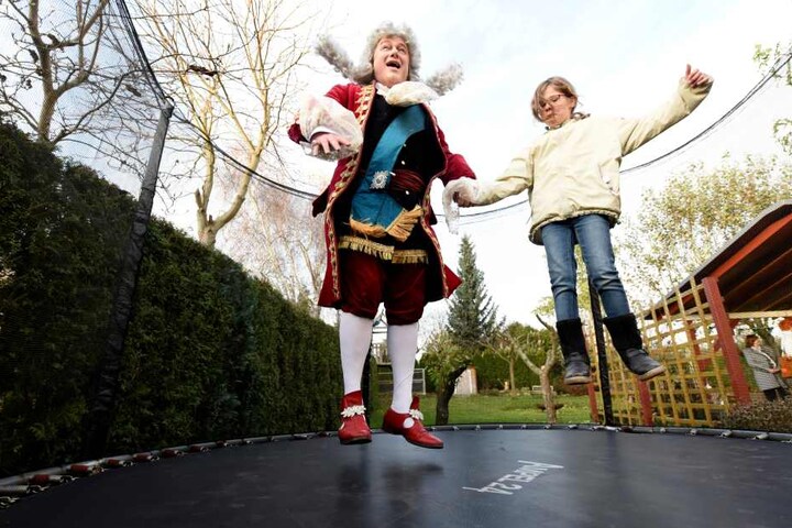 Kurfürst August hopst mit Ronja im Trampolin - Perücke und Rockschöße fliegen in die Luft.