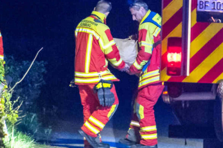 Helfer der Feuerwehr tragen einen der großen Stein von der Unfallstelle.