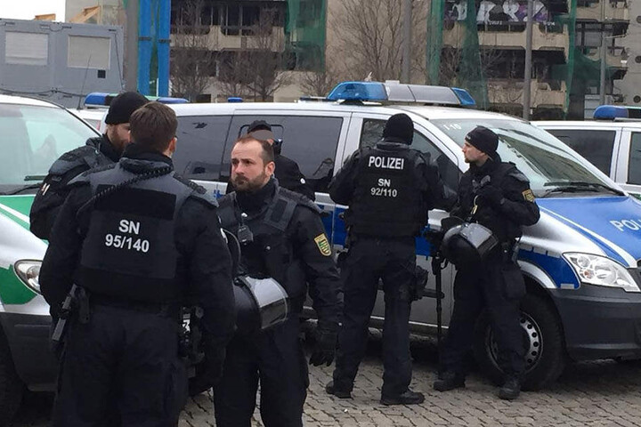 Polizeibeamte nehmen die Personalien eines Teilnehmers (im Hintergrund) auf.
