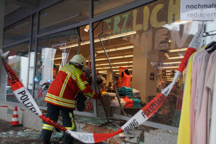 Ein Feuerwehrmann vor dem kaputten Schaufenster.